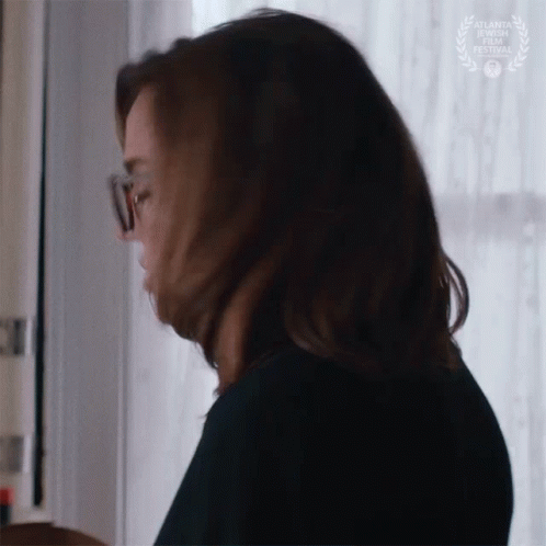A Woman Wearing Glasses Is Looking Down At Something . GIF