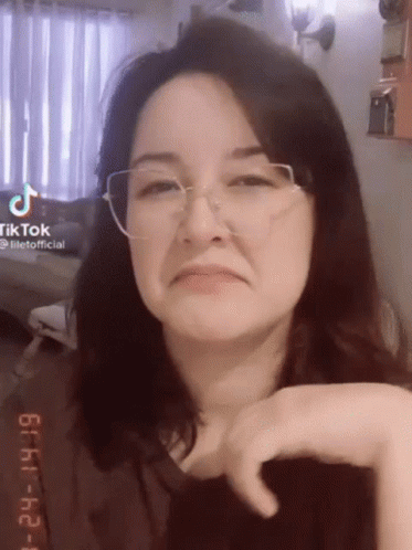 A Woman Wearing Glasses Is Making A Funny Face And Looking At The Camera . GIF