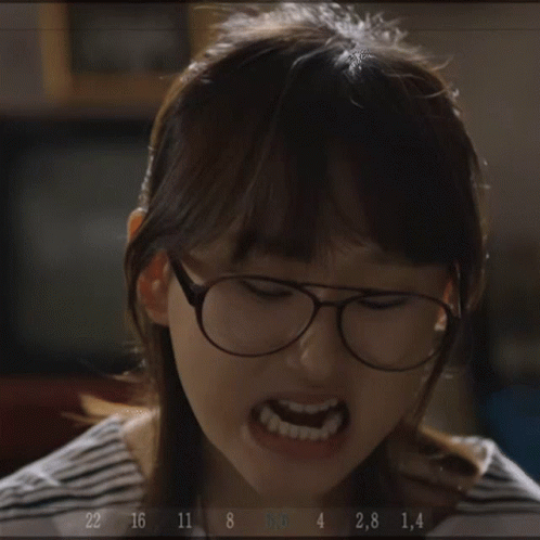 A Woman Wearing Glasses Is Making A Funny Face While Holding A Fork In Her Hand .. GIF
