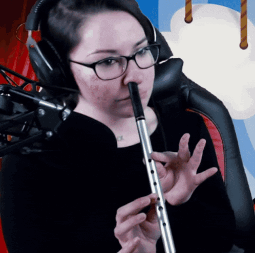 A Woman Wearing Glasses Is Playing A Flute GIF