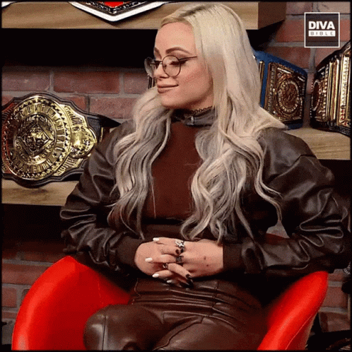 A Woman Wearing Glasses Is Sitting In A Red Chair With Diva Circle Written On The Bottom GIF