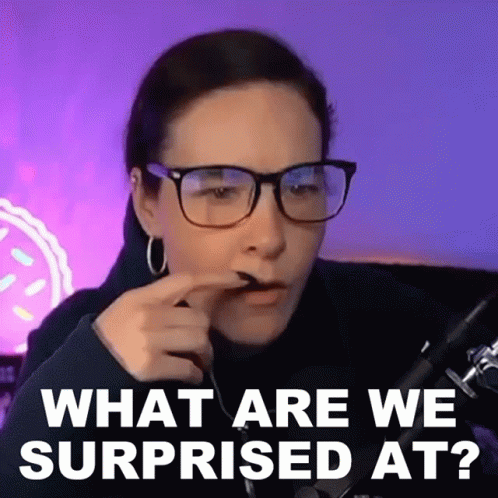 A Woman Wearing Glasses Is Sitting In Front Of A Microphone And Making A Surprised Face . GIF