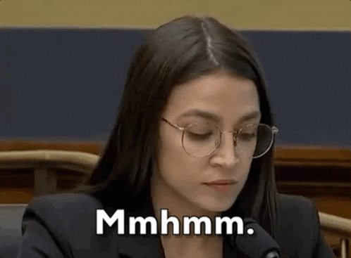 A Woman Wearing Glasses Is Sitting In Front Of A Microphone . GIF