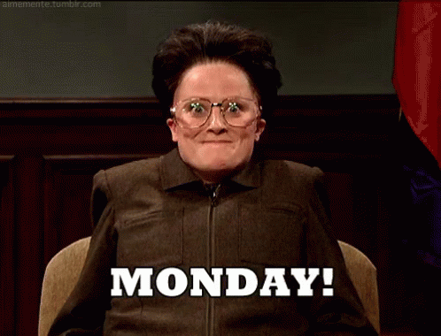 A Woman Wearing Glasses Is Sitting In Front Of A Sign That Says Monday . GIF
