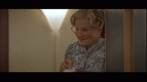 A Woman Wearing Glasses Is Standing In A Doorway GIF