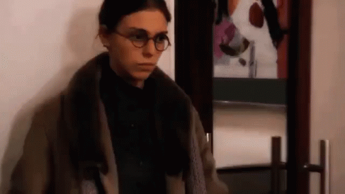 a woman wearing glasses is standing in front of a door .