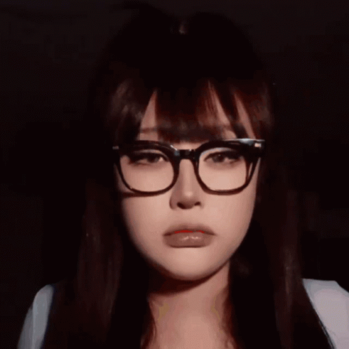 A Woman Wearing Glasses Is Sticking Out Her Red Tongue GIF