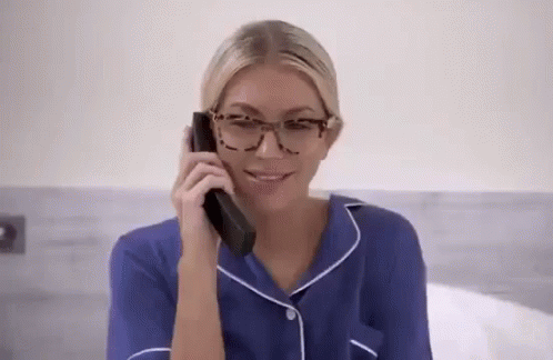 A Woman Wearing Glasses Is Talking On A Phone . GIF