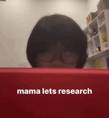 A Woman Wearing Glasses Looks At A Red Box That Says Mama Lets Research On It GIF