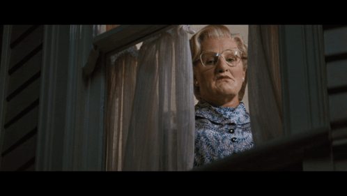 A Woman Wearing Glasses Looks Out A Window GIF