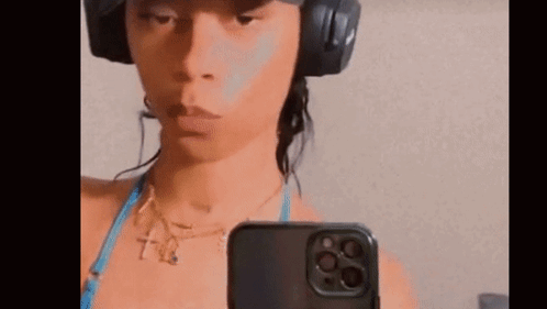 A Woman Wearing Headphones And A Bikini Is Taking A Selfie With Her Cell Phone . GIF