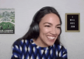A Woman Wearing Headphones And A Blue Shirt Is Smiling And Laughing . GIF