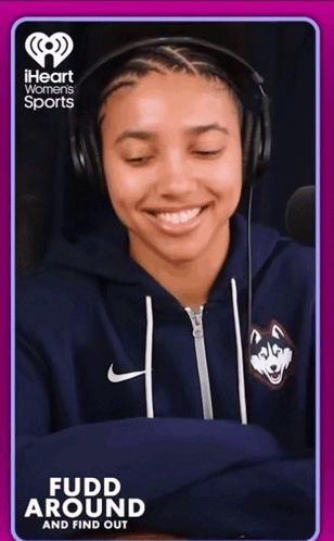 A Woman Wearing Headphones And A Blue Sweatshirt With A Husky On It Is On A Iheart Women 'S Sports Ad GIF