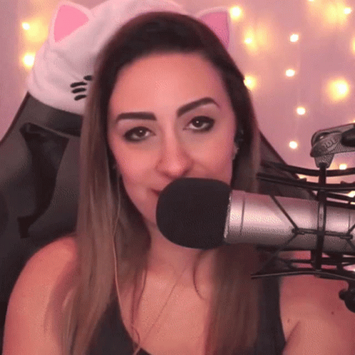A Woman Wearing Headphones And A Cat Ear Hat Is Talking Into A Microphone GIF