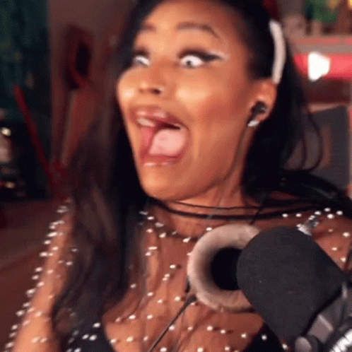 A Woman Wearing Headphones And A Headband Is Making A Funny Face In Front Of A Microphone GIF