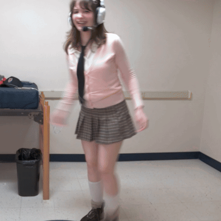 A Woman Wearing Headphones And A Pink Sweater Is Standing In A Room GIF