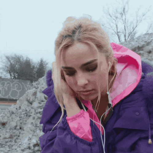 A Woman Wearing Headphones And A Purple Jacket With A Pink Hood GIF