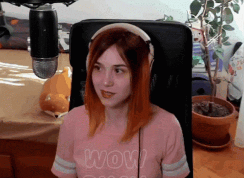 A Woman Wearing Headphones And A Shirt That Says Wow Is Sitting In Front Of A Microphone GIF