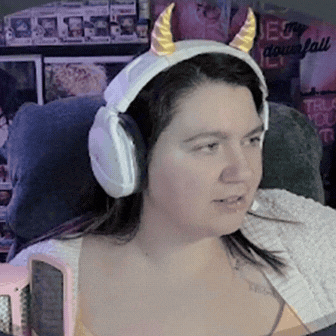 a woman wearing headphones and a unicorn headband looks at the camera