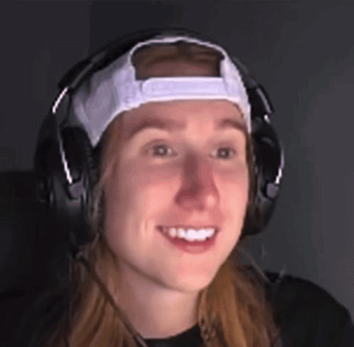 a woman wearing headphones and a white hat smiles for the camera