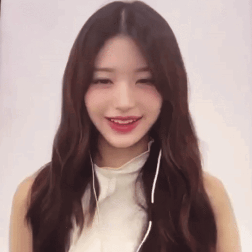 A Woman Wearing Headphones And A White Top Smiles GIF