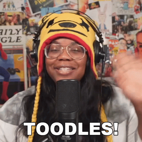 a woman wearing headphones and a winnie the pooh hat says " toodles " in front of a microphone