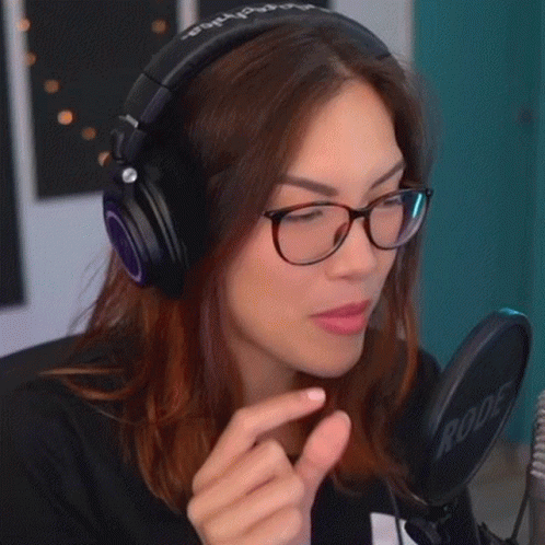 A Woman Wearing Headphones And Glasses Is Making A Funny Face GIF