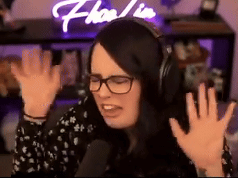 A Woman Wearing Headphones And Glasses Is Sitting In Front Of A Microphone . GIF