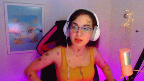 A Woman Wearing Headphones And Glasses Is Talking Into A Microphone GIF