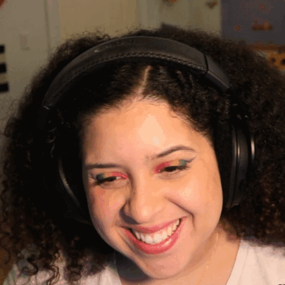 A Woman Wearing Headphones And Red Eye Shadow Smiles GIF