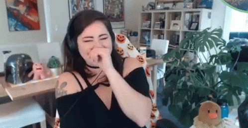 A Woman Wearing Headphones Is Covering Her Nose While Sitting In A Chair In A Living Room . GIF