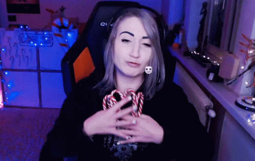 A Woman Wearing Headphones Is Holding A Candy Cane In Her Hand GIF