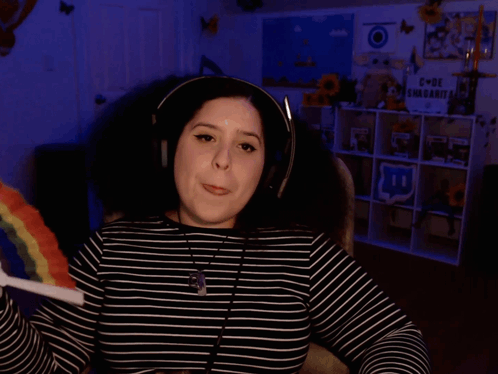 A Woman Wearing Headphones Is Holding A Rainbow Lollipop And Says I Have Tons Of Questions GIF
