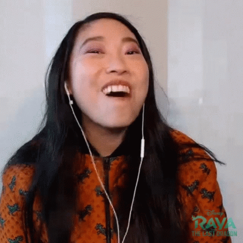 A Woman Wearing Headphones Is Laughing While Watching A Video . GIF