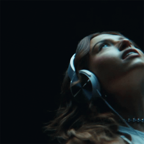 A Woman Wearing Headphones Is Listening To Music GIF