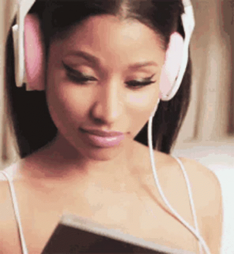 A Woman Wearing Headphones Is Listening To Music And Looking At A Book . GIF