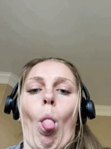 A Woman Wearing Headphones Is Making A Funny Face GIF