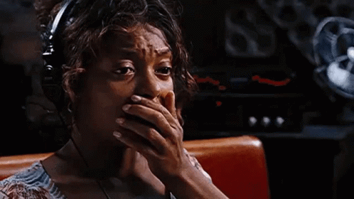 A Woman Wearing Headphones Is Sitting In A Diner And Covering Her Mouth With Her Hands . GIF