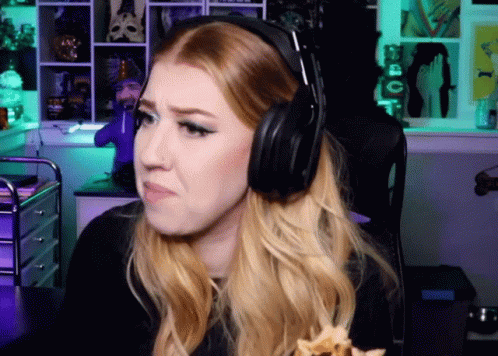 A Woman Wearing Headphones Is Sitting In Front Of A Green Wall GIF