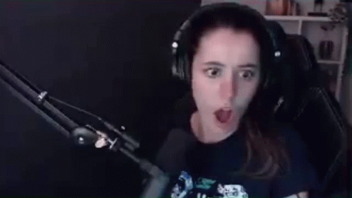 A Woman Wearing Headphones Is Sitting In Front Of A Microphone Making A Funny Face . GIF