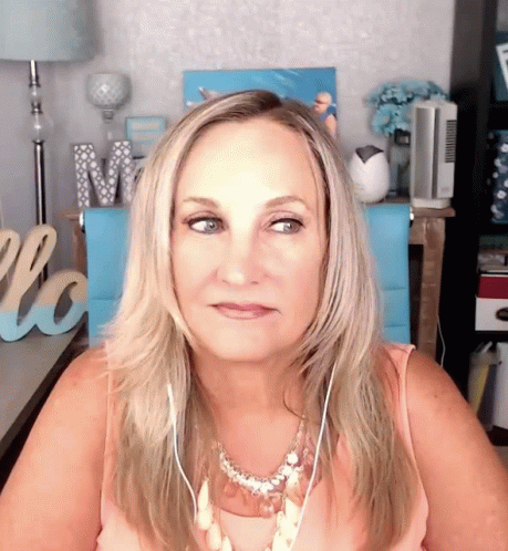 A Woman Wearing Headphones Is Sitting In Front Of A Welcome Sign GIF