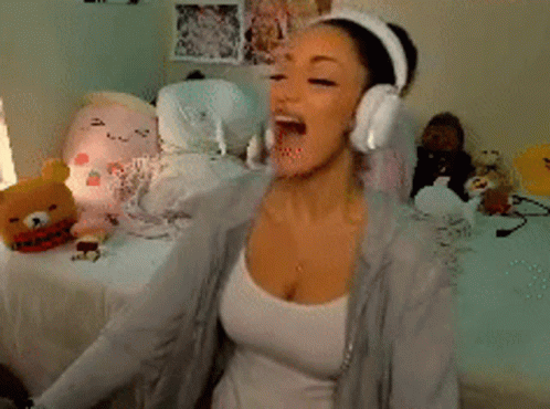 A Woman Wearing Headphones Is Sitting On A Bed In Front Of Stuffed Animals GIF