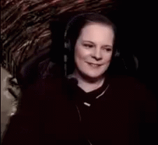 A Woman Wearing Headphones Is Smiling And Says " Witch Cackling " GIF