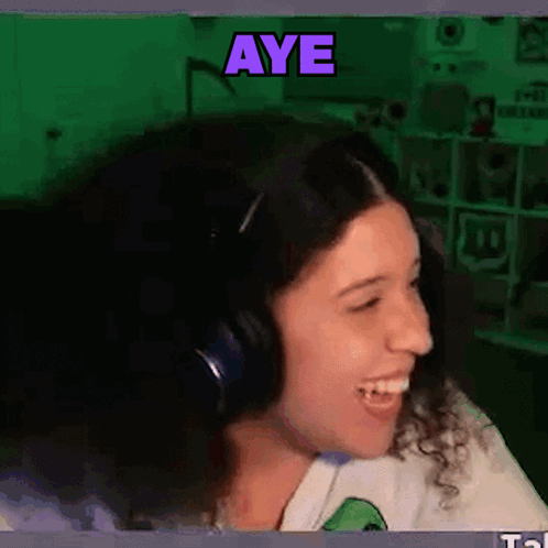 A Woman Wearing Headphones Is Smiling With The Word Aye Written Above Her GIF