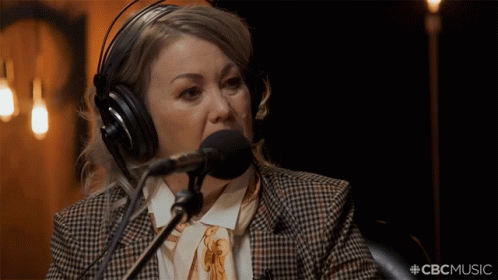 A Woman Wearing Headphones Is Speaking Into A Microphone With The Hashtag #Cbcmusic GIF