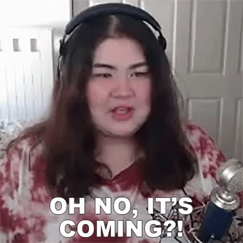 A Woman Wearing Headphones Is Talking Into A Microphone And Says `` Oh No , It 'S Coming '' . GIF