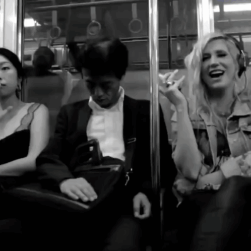 A Woman Wearing Headphones Laughs While Sitting Next To A Man GIF