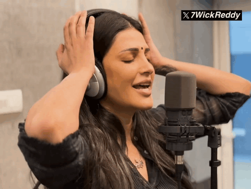 A Woman Wearing Headphones Singing Into A Microphone With A 7Wickreddy Logo In The Corner GIF