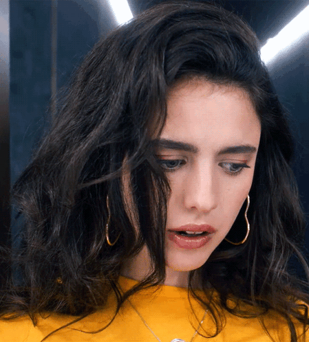 A Woman Wearing Hoop Earrings And A Yellow Shirt GIF