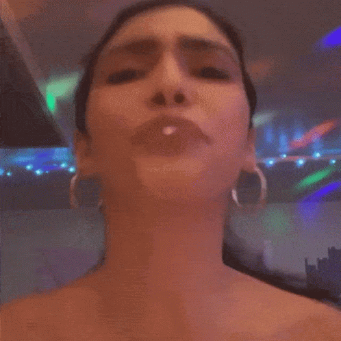 A Woman Wearing Hoop Earrings Is Making A Face GIF